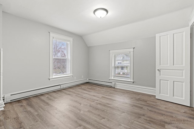 additional living space featuring light wood-type flooring, baseboard heating, a wealth of natural light, and lofted ceiling