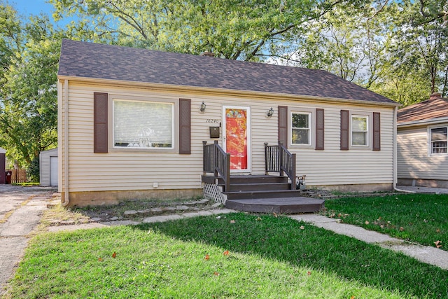 view of front of house with an outdoor structure and a front lawn