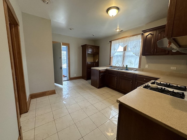 kitchen featuring dark brown cabinets, sink, and light tile patterned flooring