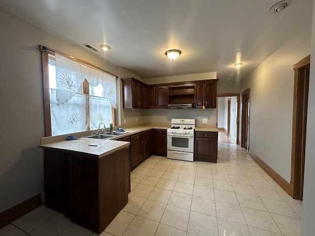 kitchen featuring sink, white gas range oven, light tile patterned floors, dark brown cabinets, and kitchen peninsula