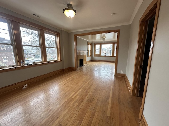 unfurnished living room with plenty of natural light, crown molding, and light hardwood / wood-style flooring