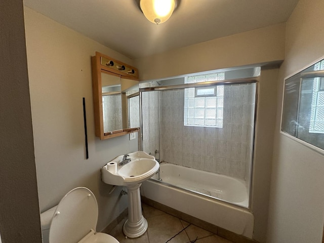 bathroom featuring tile patterned flooring, enclosed tub / shower combo, and toilet