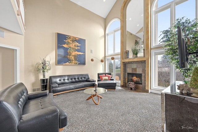 carpeted living room with a tile fireplace and a high ceiling