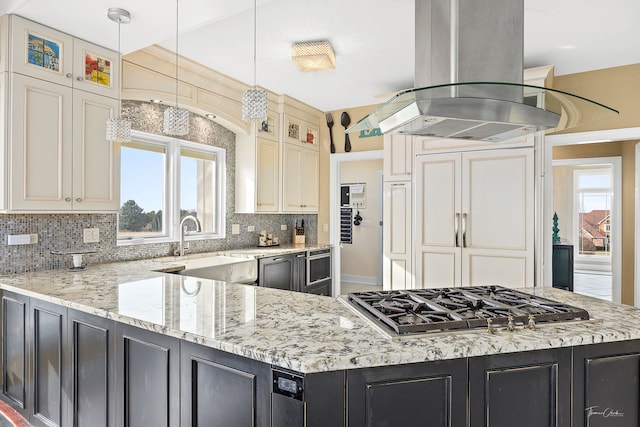 kitchen featuring pendant lighting, cream cabinets, light stone countertops, island exhaust hood, and stainless steel gas cooktop