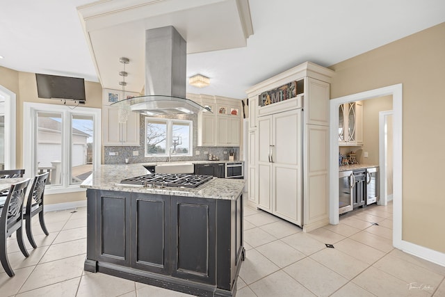 kitchen featuring island exhaust hood, light stone counters, a kitchen island, and cream cabinetry