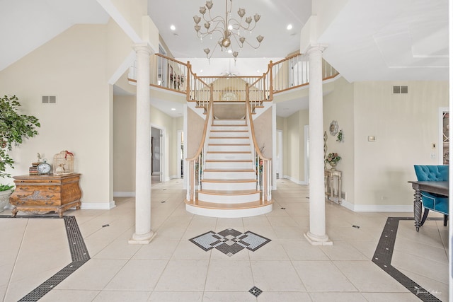 entrance foyer with light tile patterned flooring, ornate columns, a towering ceiling, and an inviting chandelier