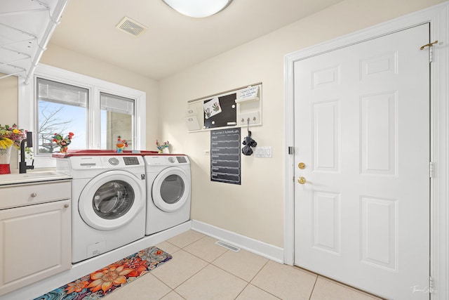laundry area with a sink, light tile patterned flooring, baseboards, visible vents, and independent washer and dryer