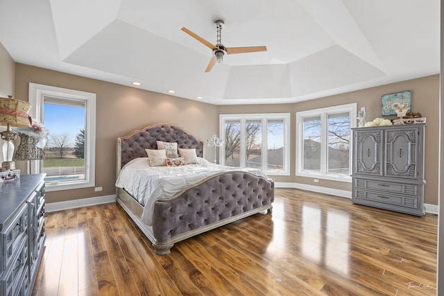 bedroom with hardwood / wood-style floors, a raised ceiling, and ceiling fan