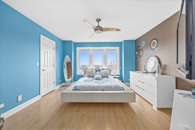 bedroom with light wood-type flooring, a ceiling fan, and baseboards