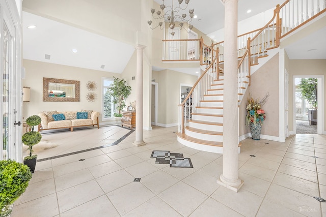 foyer entrance featuring light tile patterned floors, a towering ceiling, decorative columns, and a wealth of natural light