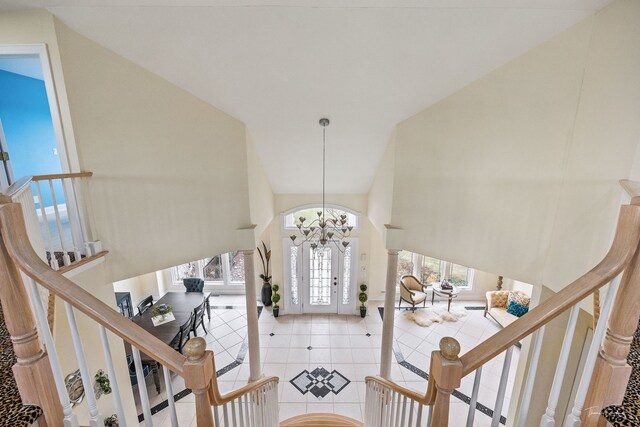 entryway featuring high vaulted ceiling, an inviting chandelier, tile patterned floors, and stairs