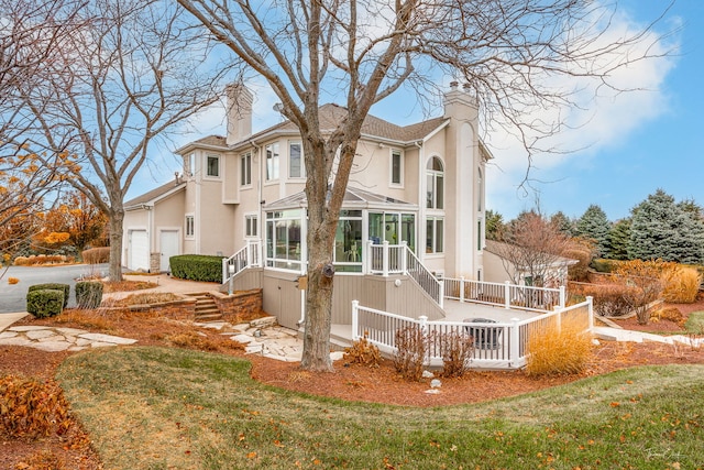 rear view of property featuring stairway, a chimney, stucco siding, concrete driveway, and a sunroom