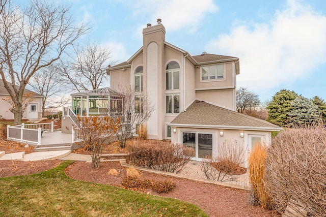 back of property featuring a wooden deck, a chimney, a gazebo, and stucco siding