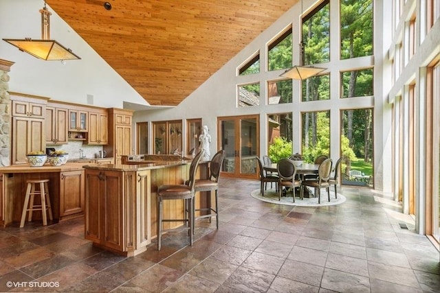 kitchen featuring a kitchen breakfast bar, backsplash, wood ceiling, high vaulted ceiling, and a kitchen island