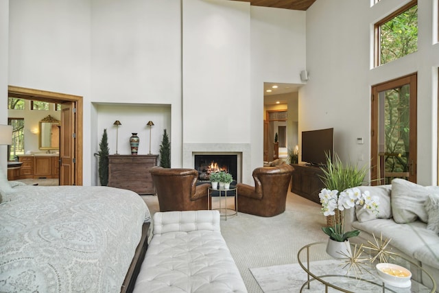 bedroom featuring carpet flooring, ensuite bathroom, and a high ceiling