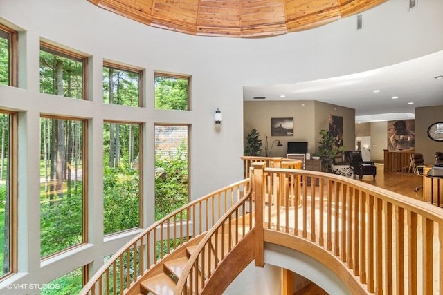 staircase with hardwood / wood-style flooring, plenty of natural light, and a high ceiling