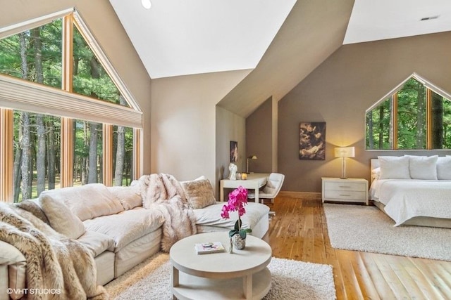 living room featuring a wealth of natural light, high vaulted ceiling, and wood-type flooring