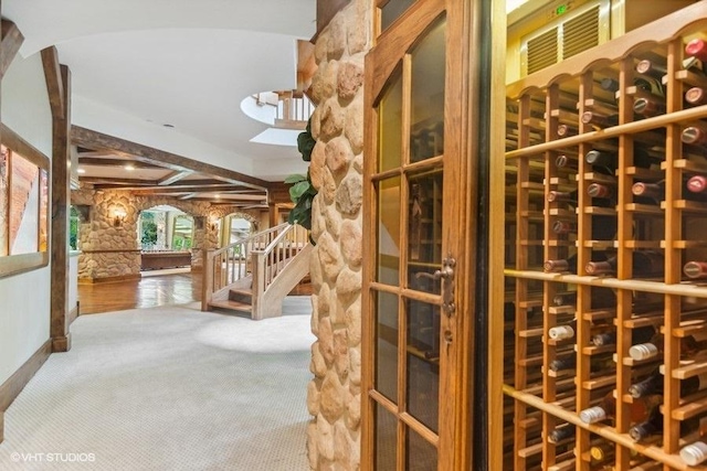 wine area featuring beamed ceiling and carpet floors