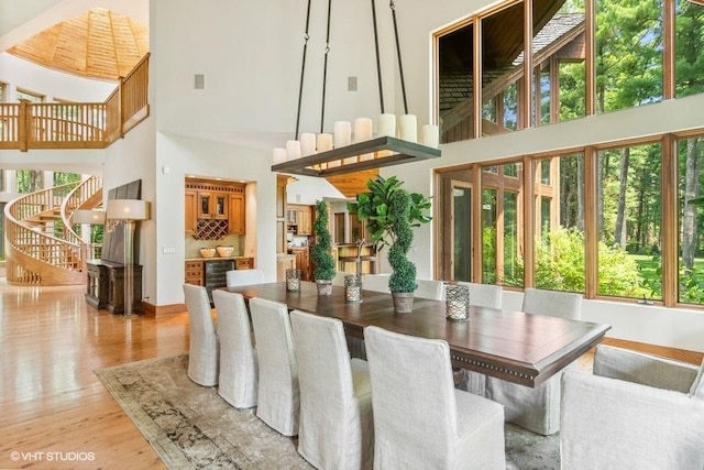 dining area featuring bar, wine cooler, light hardwood / wood-style flooring, and a towering ceiling