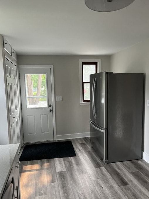 kitchen featuring stainless steel fridge, dark wood-type flooring, light stone counters, and a healthy amount of sunlight