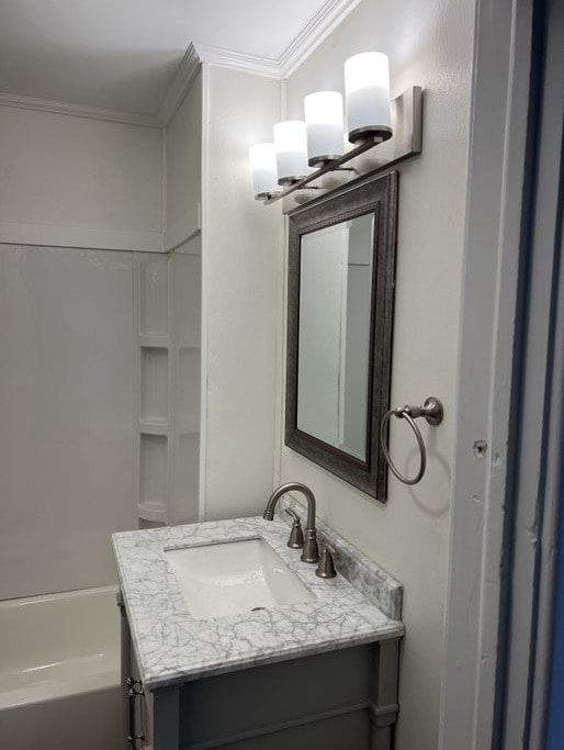 bathroom featuring vanity, ornamental molding, and a washtub