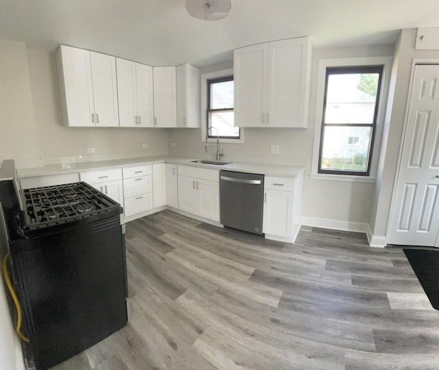 kitchen with stainless steel dishwasher, sink, light hardwood / wood-style flooring, white cabinets, and black range with electric stovetop