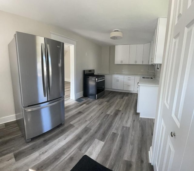 kitchen with appliances with stainless steel finishes, dark hardwood / wood-style flooring, white cabinetry, and sink