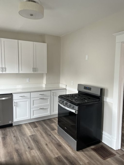 kitchen with hardwood / wood-style floors, white cabinets, and appliances with stainless steel finishes