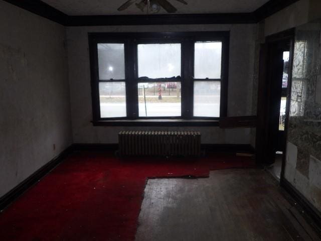 unfurnished room with ceiling fan, hardwood / wood-style flooring, radiator heating unit, and a healthy amount of sunlight