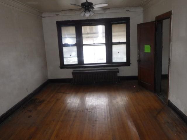 empty room featuring crown molding, radiator heating unit, and dark hardwood / wood-style floors