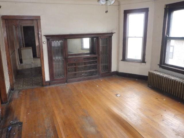 unfurnished living room featuring wood-type flooring and radiator heating unit