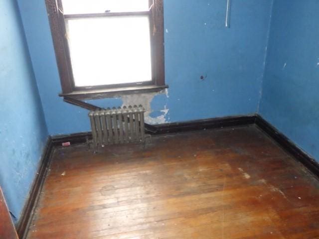 spare room with dark wood-type flooring and radiator heating unit