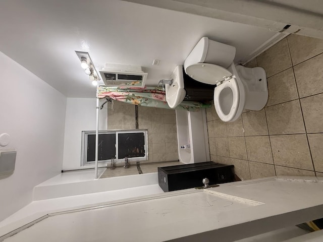 bathroom featuring toilet and tile walls