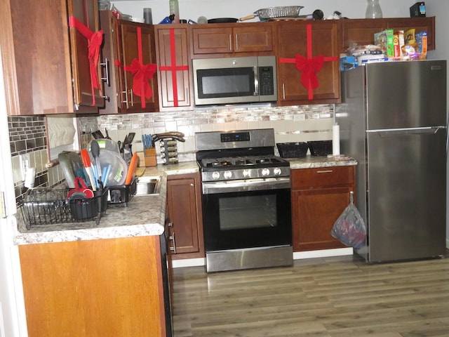 kitchen featuring dark hardwood / wood-style flooring, appliances with stainless steel finishes, and tasteful backsplash