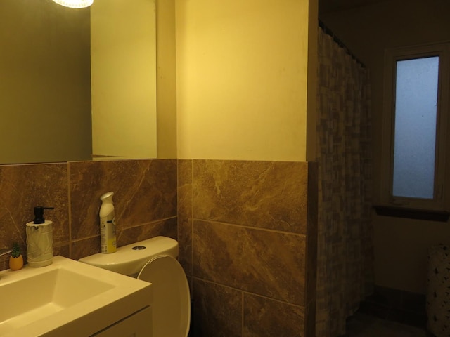 bathroom featuring vanity, toilet, and tile walls