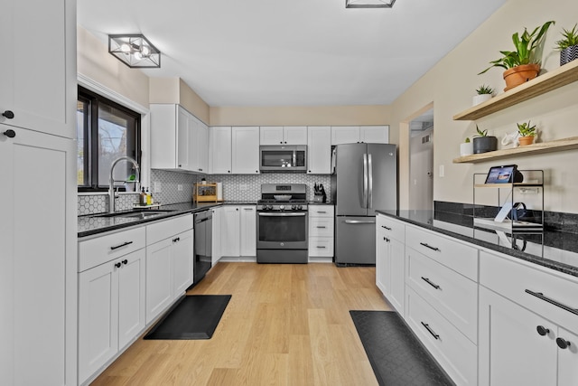 kitchen with decorative backsplash, light wood-type flooring, stainless steel appliances, sink, and white cabinets