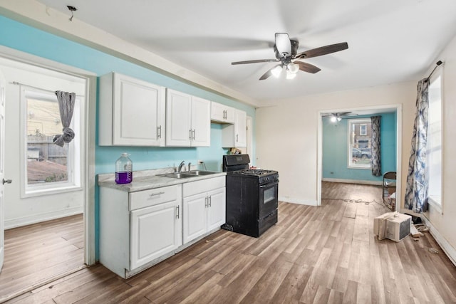 kitchen with black gas range, ceiling fan, sink, light hardwood / wood-style flooring, and white cabinets