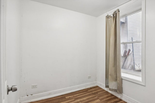 empty room featuring a wealth of natural light and dark hardwood / wood-style flooring