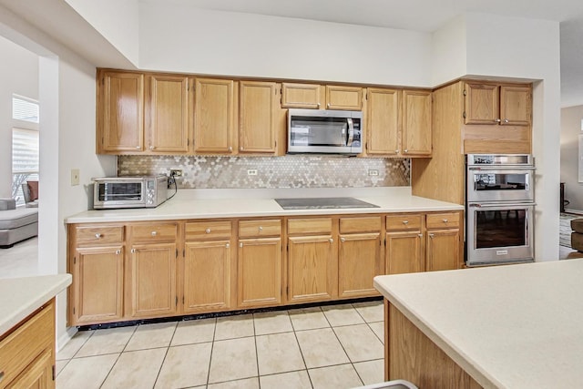 kitchen with decorative backsplash, light tile patterned floors, and stainless steel appliances