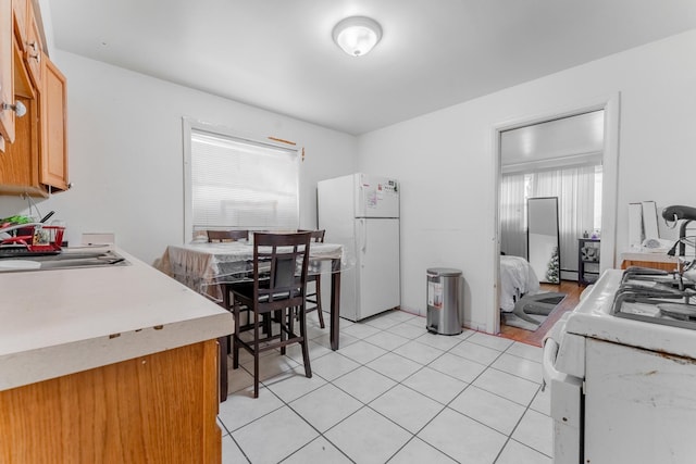 kitchen with sink, light tile patterned floors, and white fridge