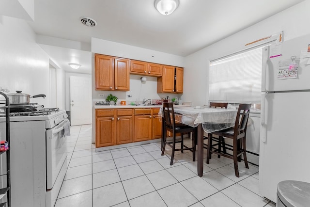 kitchen with white appliances, light tile patterned flooring, and sink