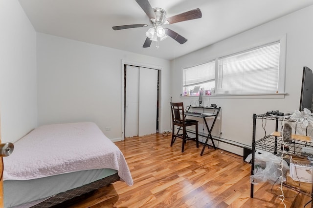 bedroom featuring ceiling fan, baseboard heating, hardwood / wood-style floors, and a closet