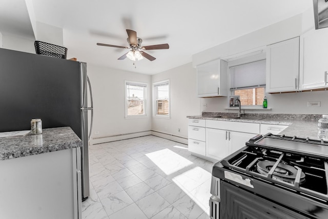 kitchen featuring sink, gas range, ceiling fan, and white cabinetry