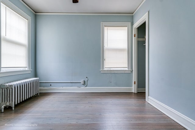 unfurnished room with wood-type flooring, plenty of natural light, radiator, and ornamental molding