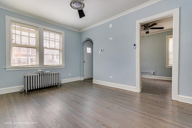 empty room featuring radiator heating unit, hardwood / wood-style flooring, ceiling fan, and crown molding