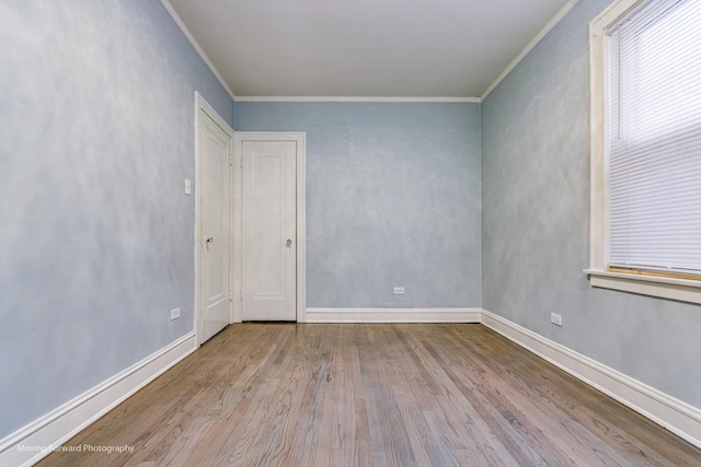 empty room with light wood-type flooring and crown molding