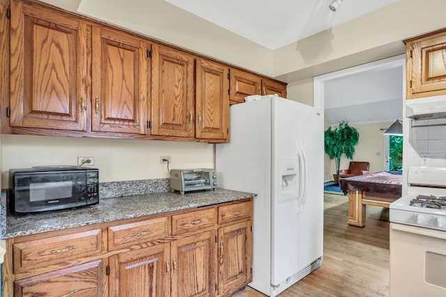 kitchen featuring light wood-type flooring, white appliances, pool table, and dark stone counters