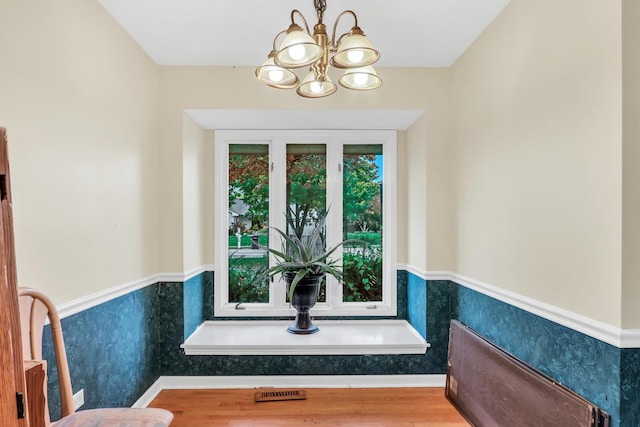 bathroom with wood-type flooring and an inviting chandelier