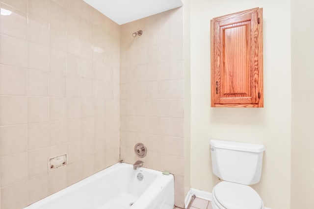 bathroom featuring tile patterned flooring, tiled shower / bath, and toilet