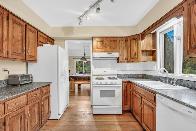 kitchen with pendant lighting, white appliances, rail lighting, sink, and light hardwood / wood-style flooring